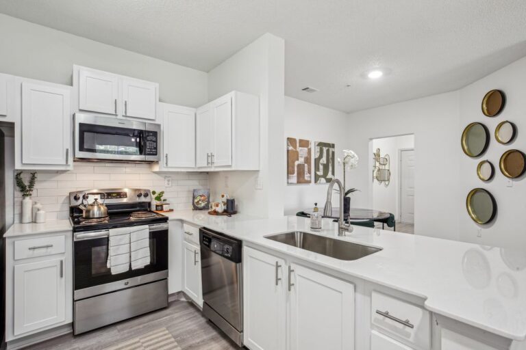 Renovated kitchen with white cabinets, wood-style floors and stainless steel appliances.