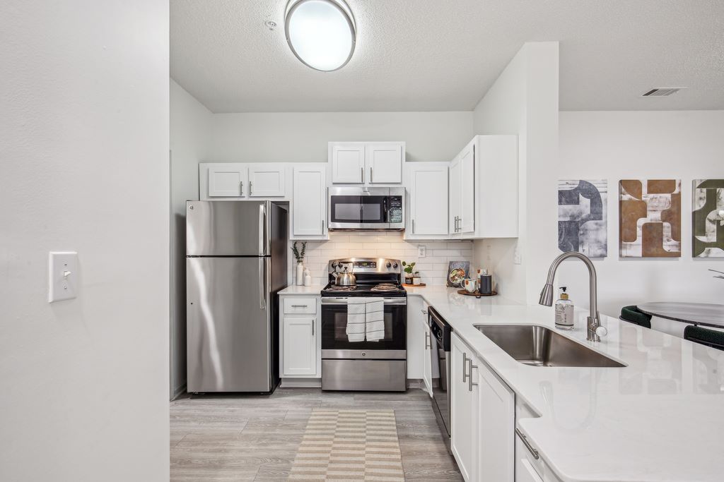 Renovated kitchen with white cabinets, wood-style floors and stainless steel appliances.