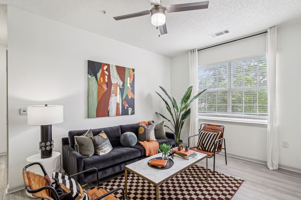 Renovated living room with furniture, modern ceiling fan and wood-style flooring.