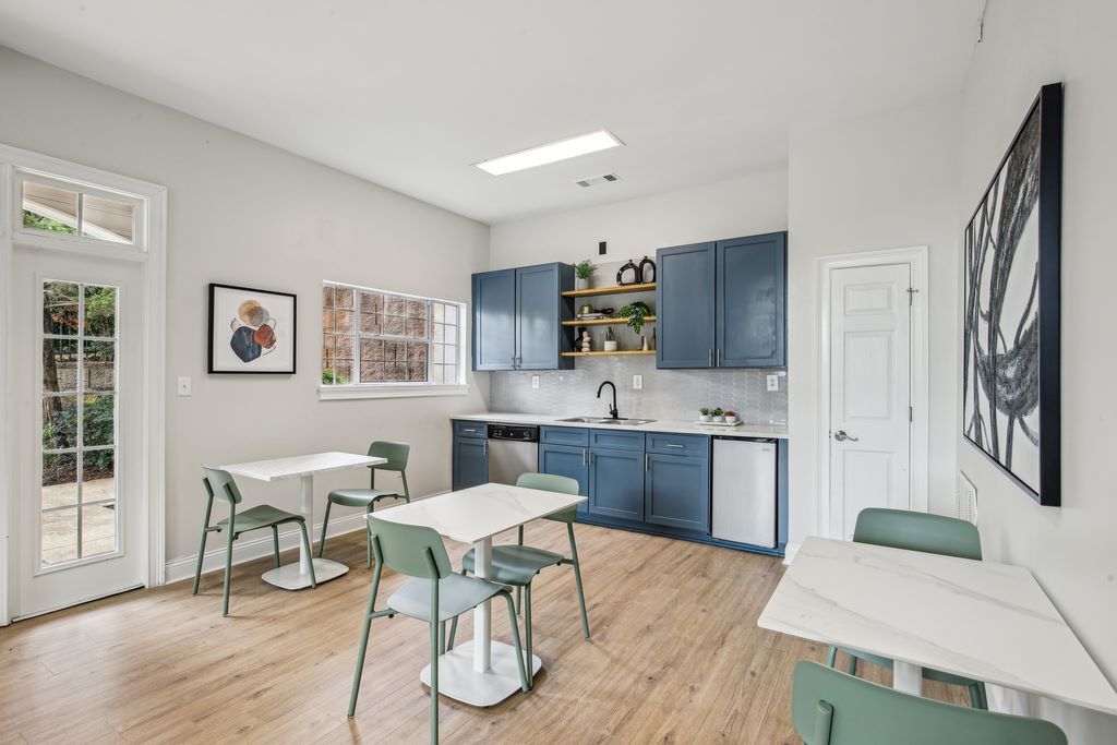 Clubhouse kitchen with hardwood-style flooring blue shaker cabinets, and three bistro tables.