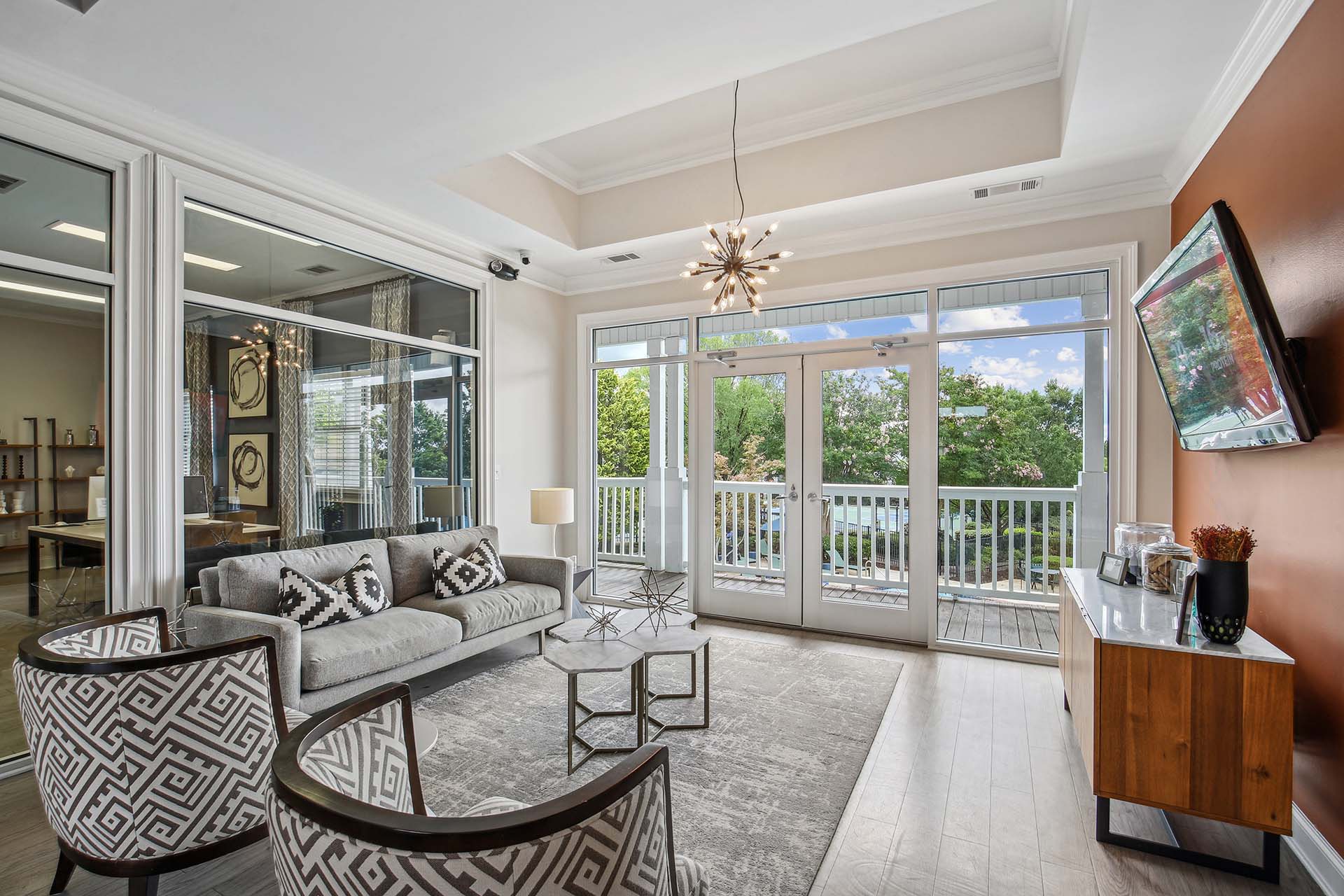 Hero image of clubhouse seating area with television hung on the wall, overlooking the pool.