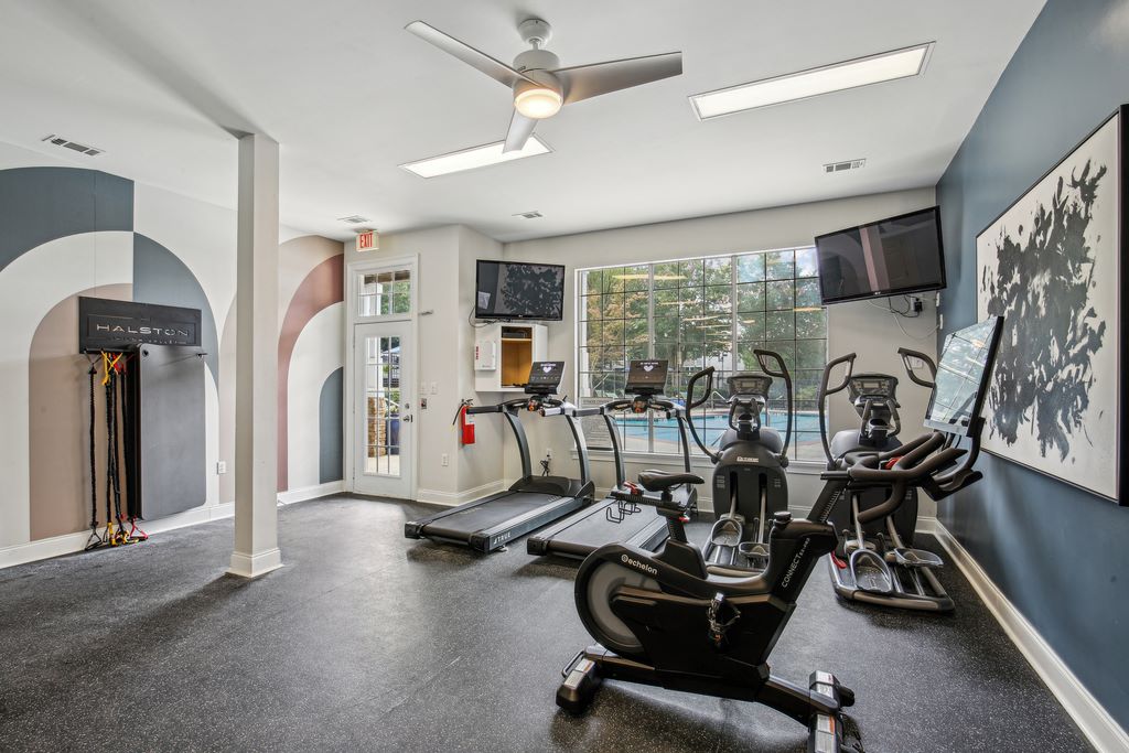 Fitness center with cardio equiptment and two televisions overlooking pool.