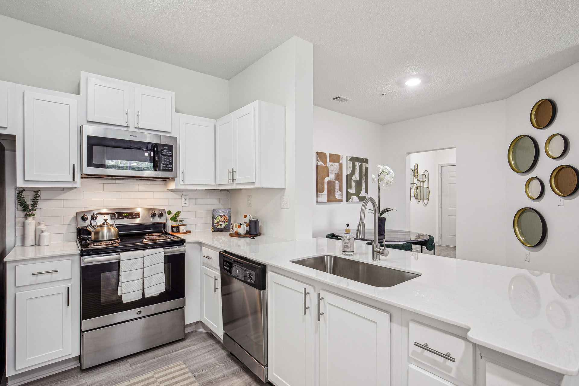 Hero image of renovated kitchen with white cabinets, wood-style floors and stainless steel appliances.