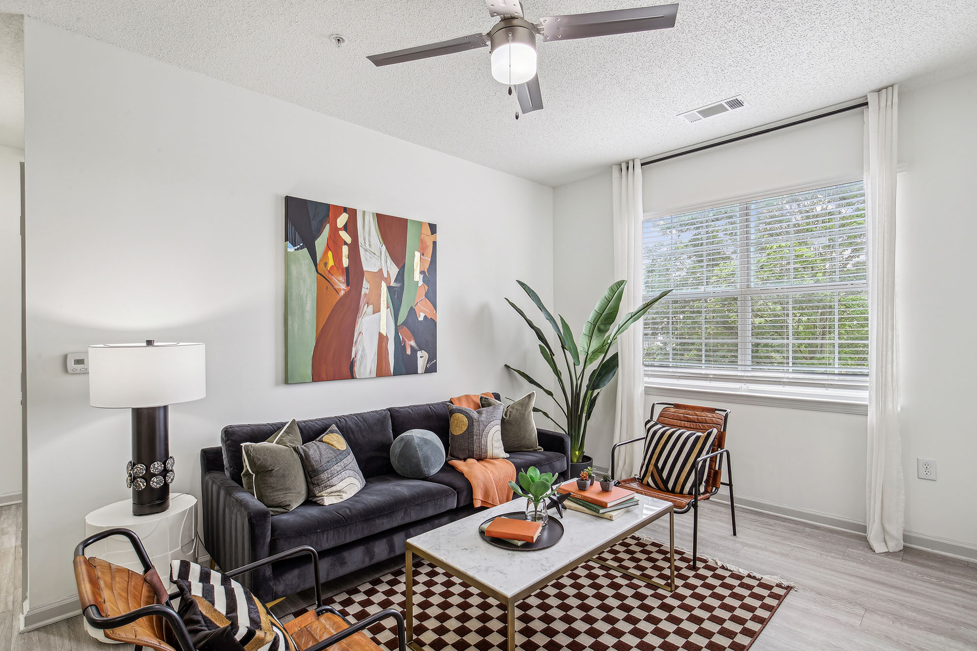 Hero image of renovated living room with furniture, modern ceiling fan and wood-style flooring.